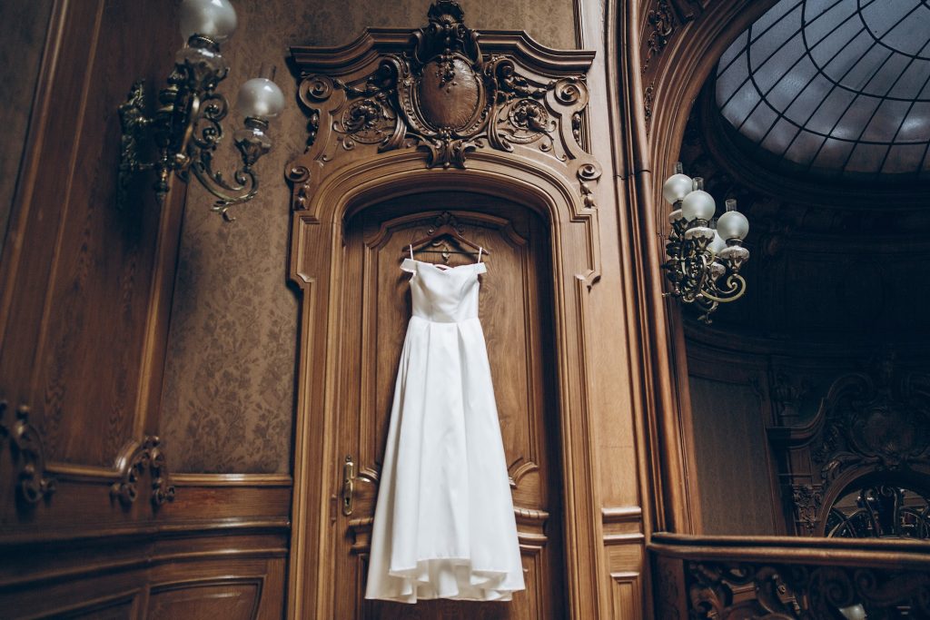 Beautiful classic silk dress hanging on old wooden wall in room